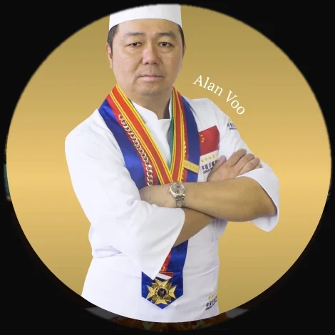 Chef Dr. Alan Voo in chef's whites and competition medals, holding a bottle of soy sauce.