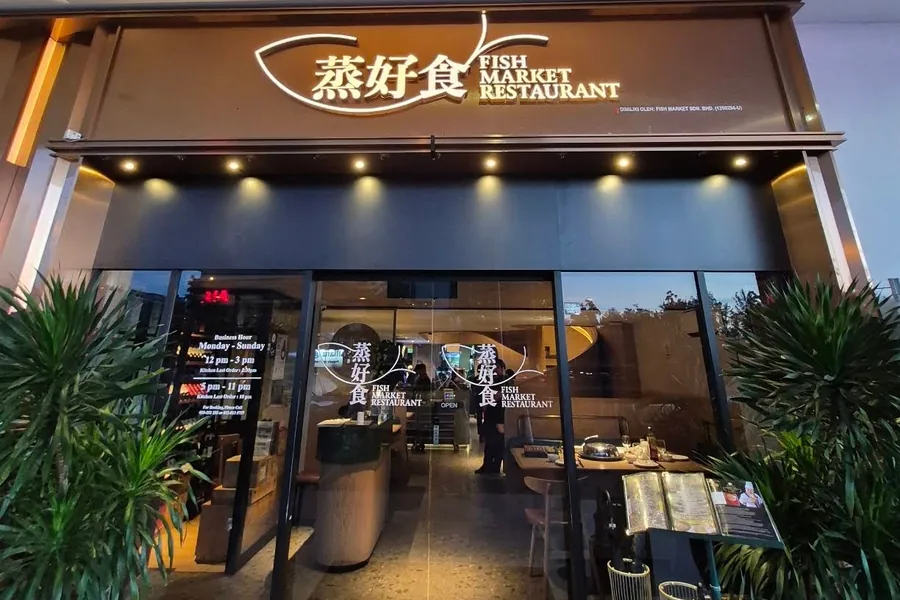 The lit shopfront on Sutera Avenue, 蒸好食 Fish Market Restaurant signage above the glass doors.